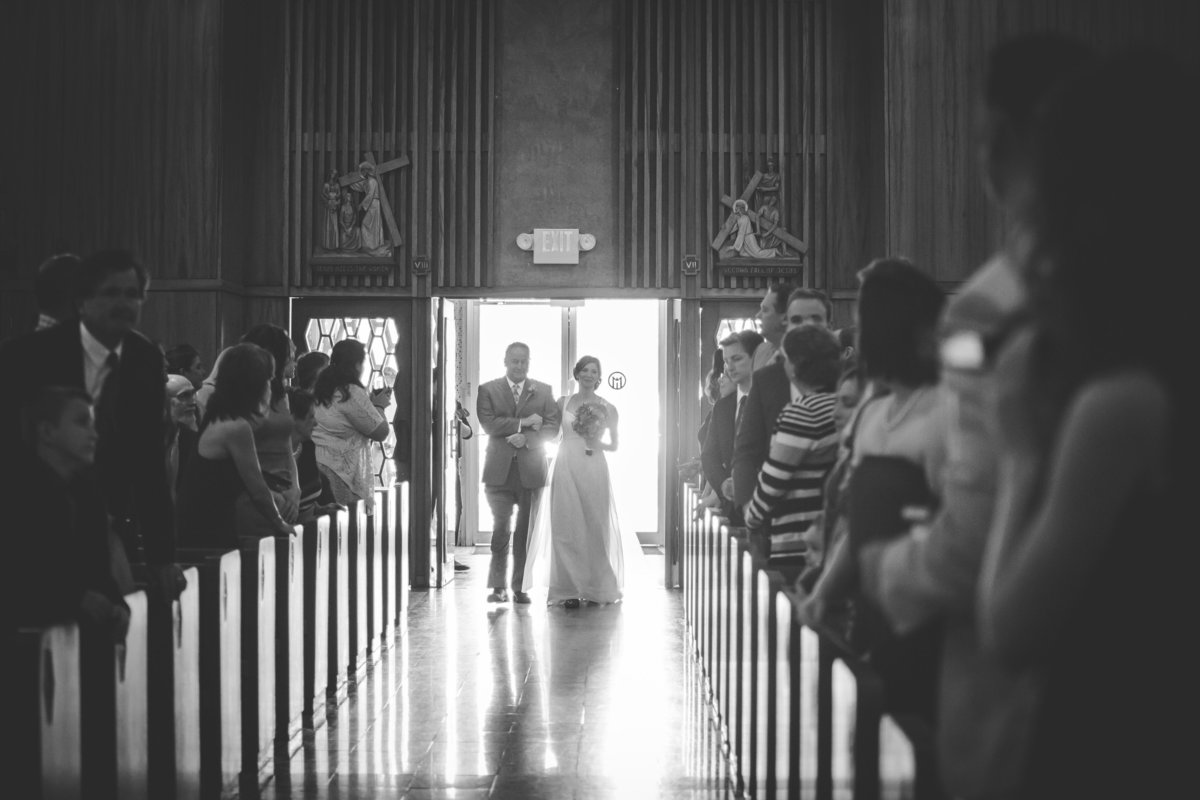 black and white photo of father walking his daughter down aisle for her wedding at Oblate School of Theology in San Antonio