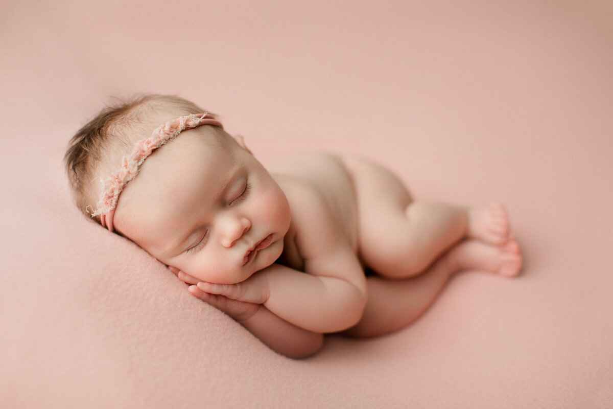 newborn baby girl on pink blanket sleeping