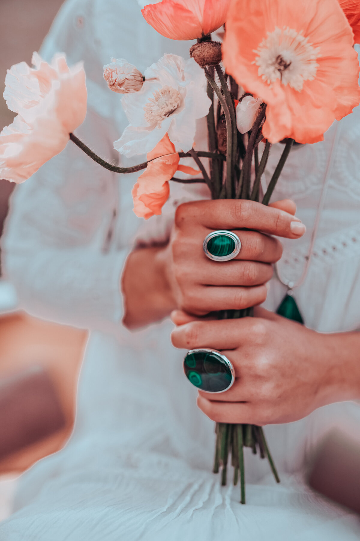 Green emerald accessories in hands surrounded by blooms