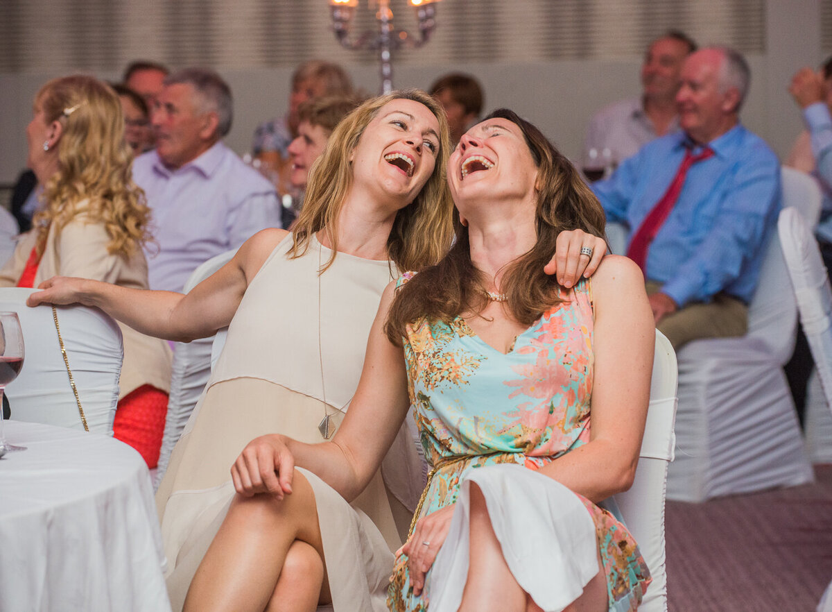 Two female wedding guests laughing at wedding reception