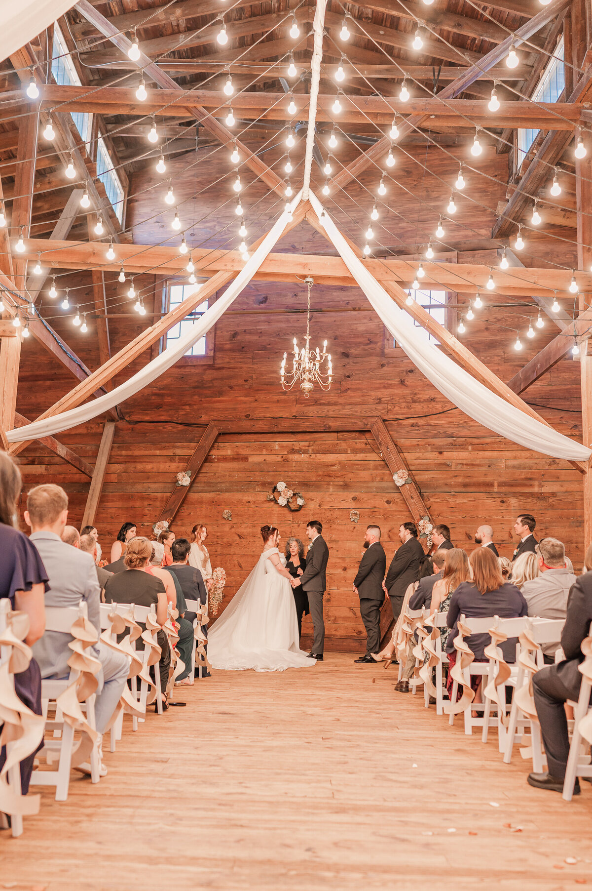 A wedding ceremony at The Peanut Warehouse under warm lighting in the fall time by Raleigh wedding photographer, JoLynn Photography