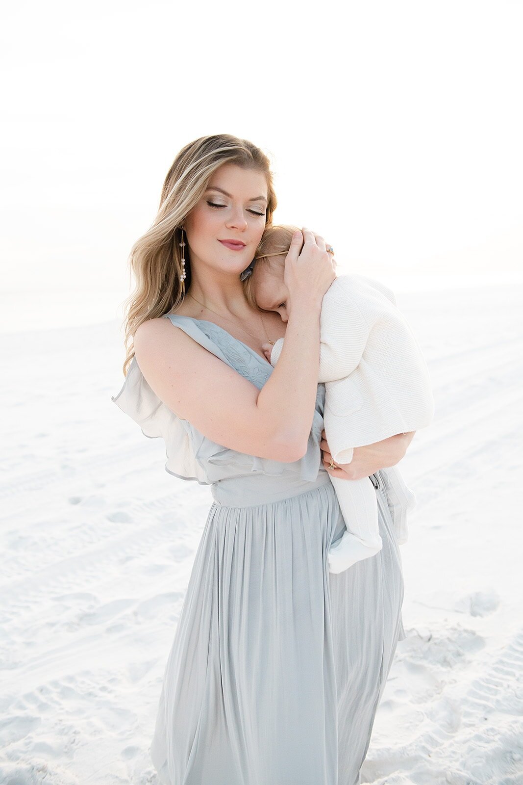a mother warming her baby at a destin beach during her family photography session