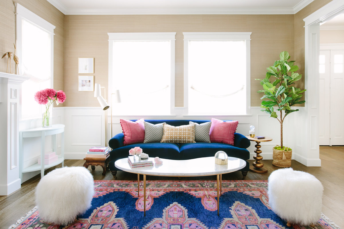 Navy and pink living room with navy velvet sofa, marble and gold coffee table, seagrass wallpaper, and Caitlin Wilson Kismet  rug