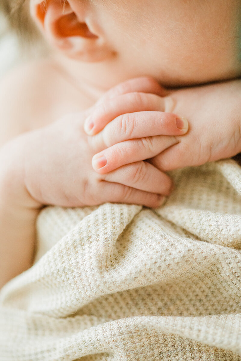 close up photo of newborn baby’s hands clasped