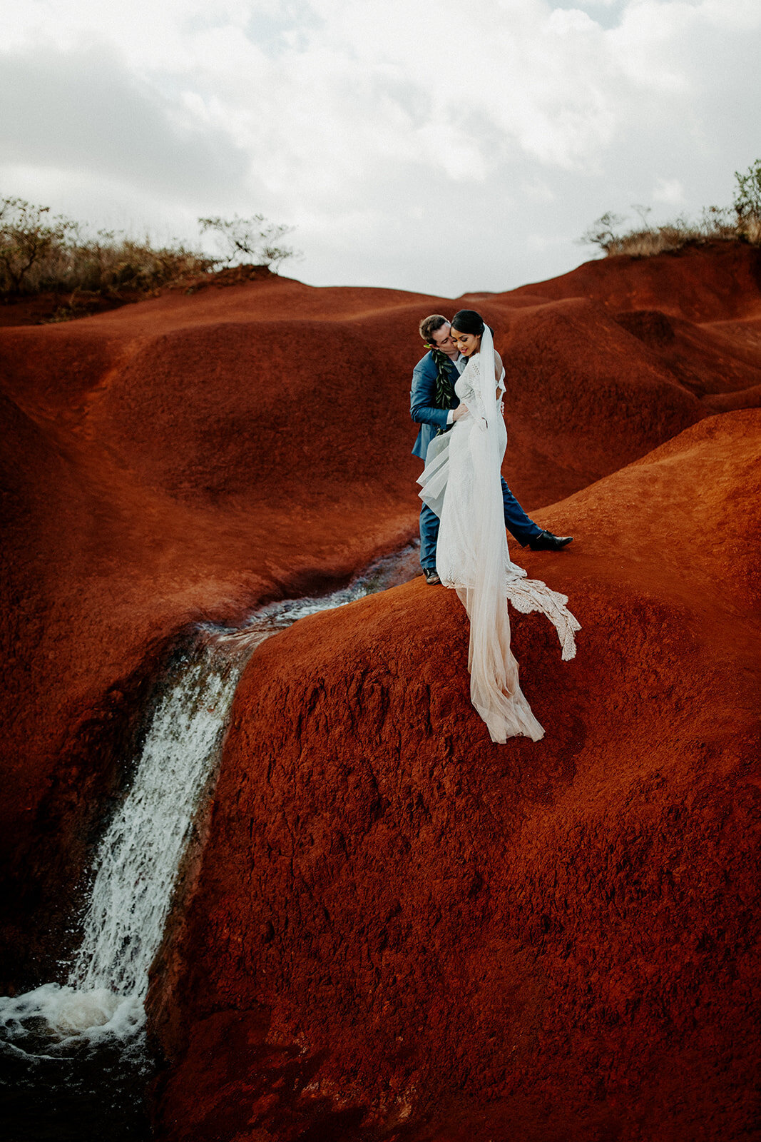 bride and groom on red cliff