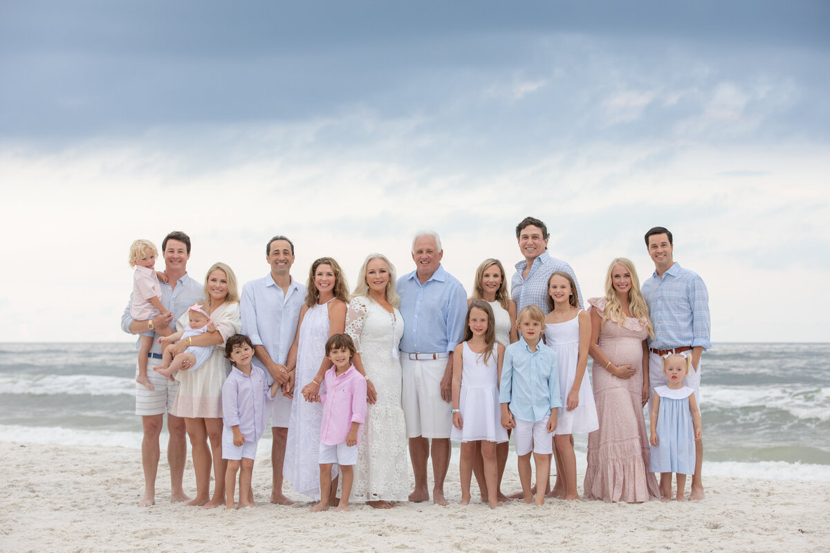 An extended family standing at the beach together smiling