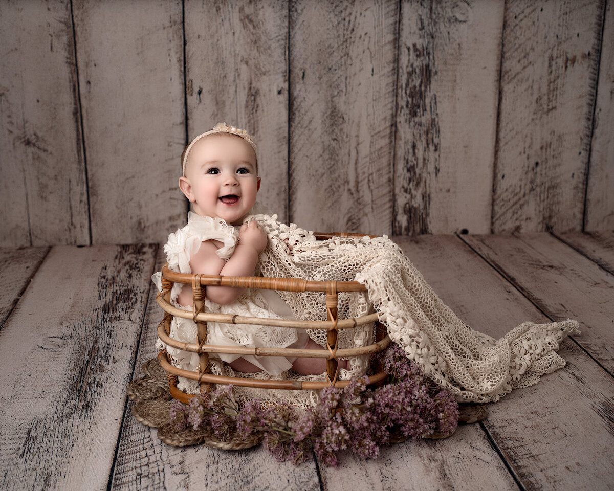 baby girl six months sitting in basket with flowers by for the love of photography Lansing