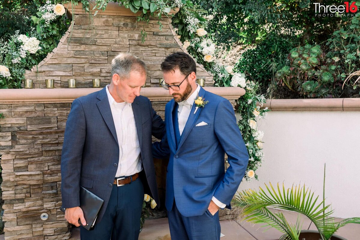 Groom and officiant share a moment in prayer before the wedding ceremony