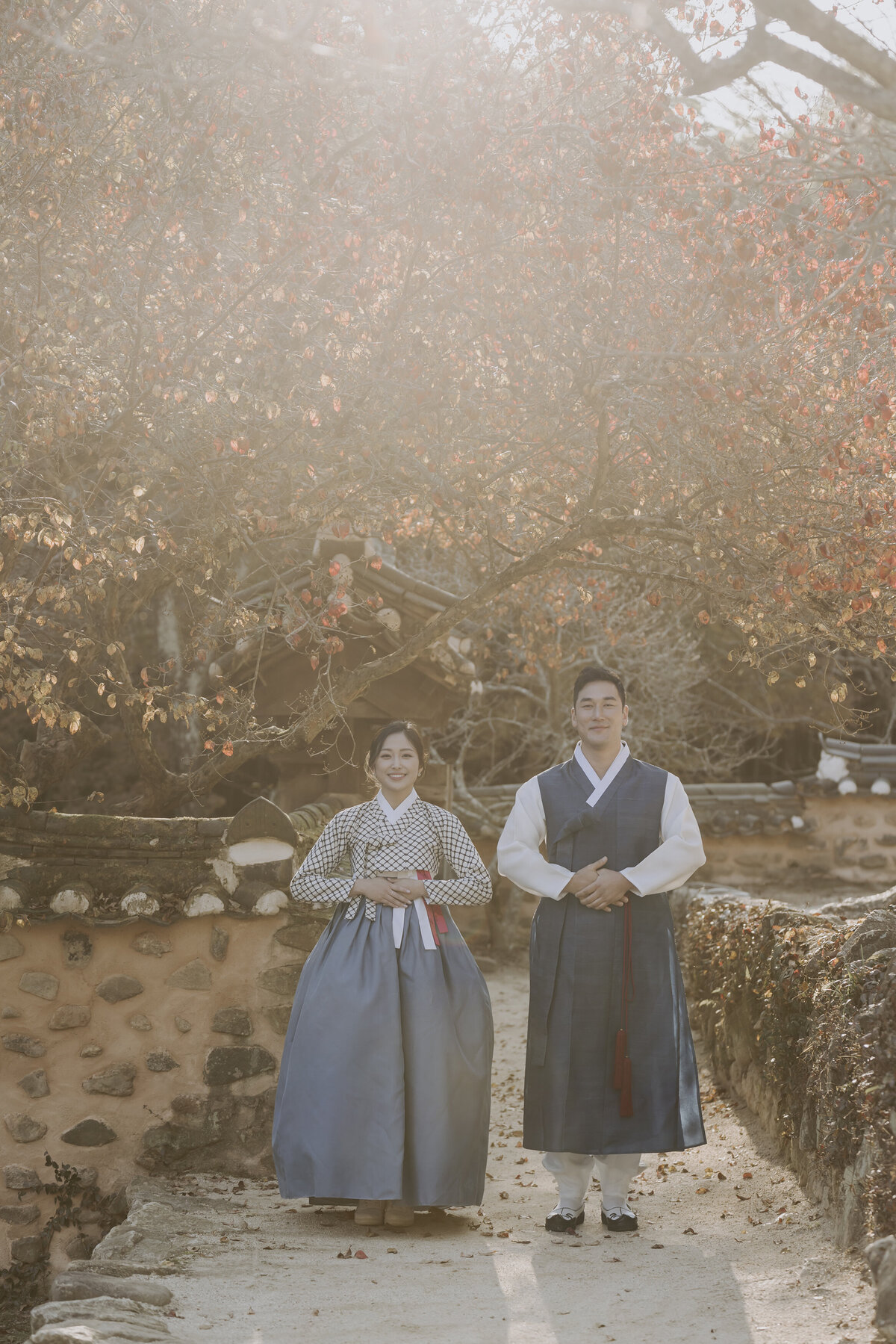 the couple wearing their blue hanbok standing in a respectful manner putting their hands at their stomach