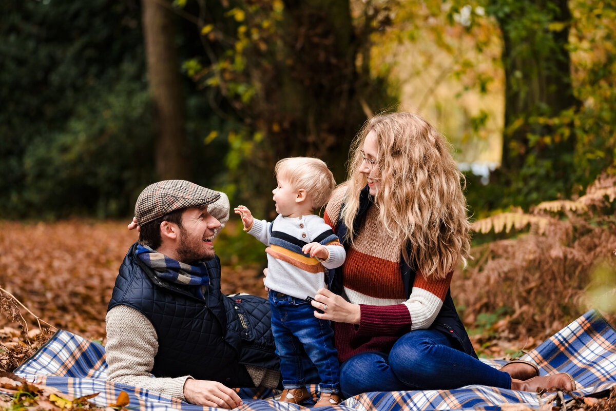 Couple with their son on blanket in autumn leaves family photoshoot