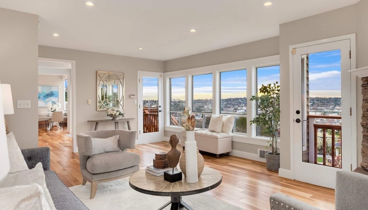 traditional luxury living room including circular coffee table, modern chairs and sculptural pieces, with neutral paint and wide-plank solid wood floors and floor to ceiling windows overlooking seattle skyline