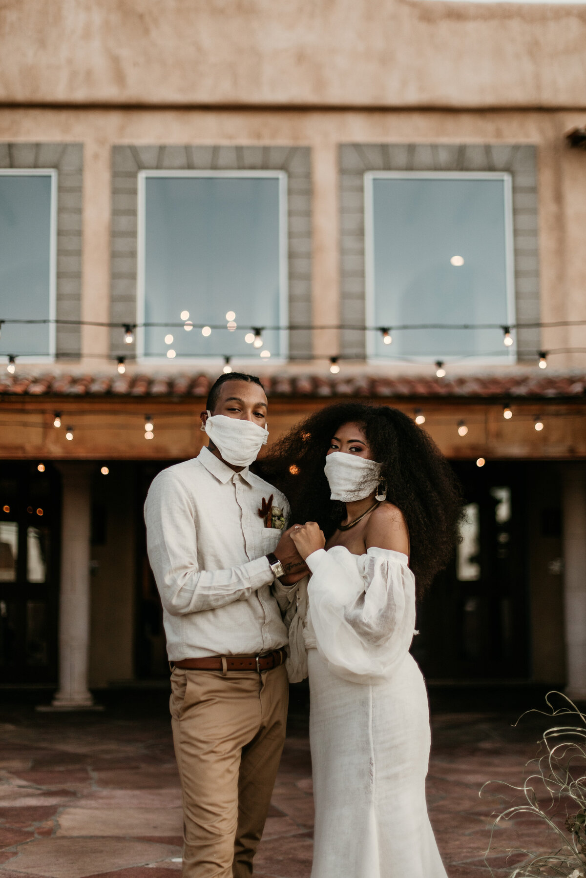 bride and groom holding hands wearing masks at Santa Fe venue courtyard wearing masks
