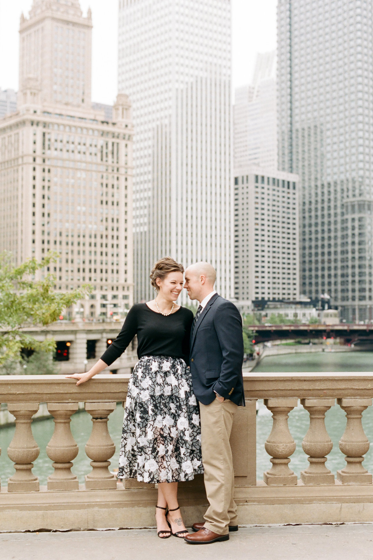 engaged couple standing in downtown chicago whispering to each other