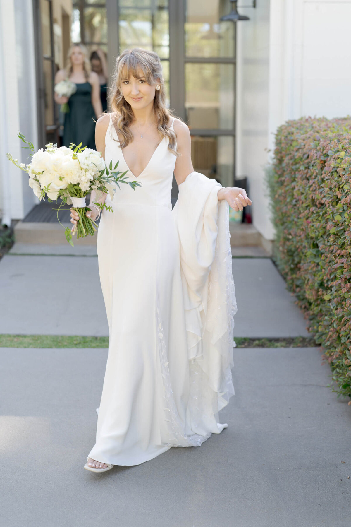 Sonoma County wedding photographer captures a bride holding a bouquet and a long train of her white gown.