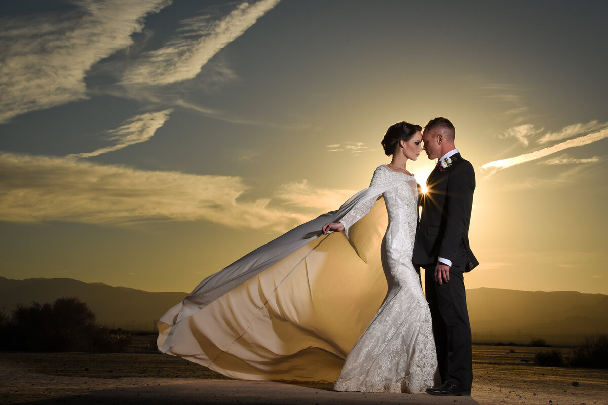 Glamorous bride and groom pose at sunset for a wedding day portrait