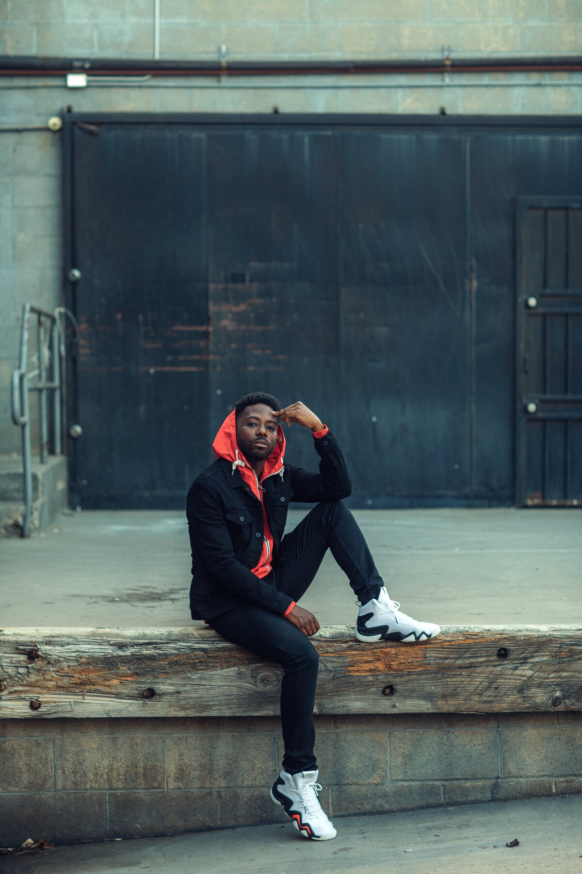 Portrait Photo Of Young Black Man In Orange Hoodie With One Hand On His Forehead Los Angeles
