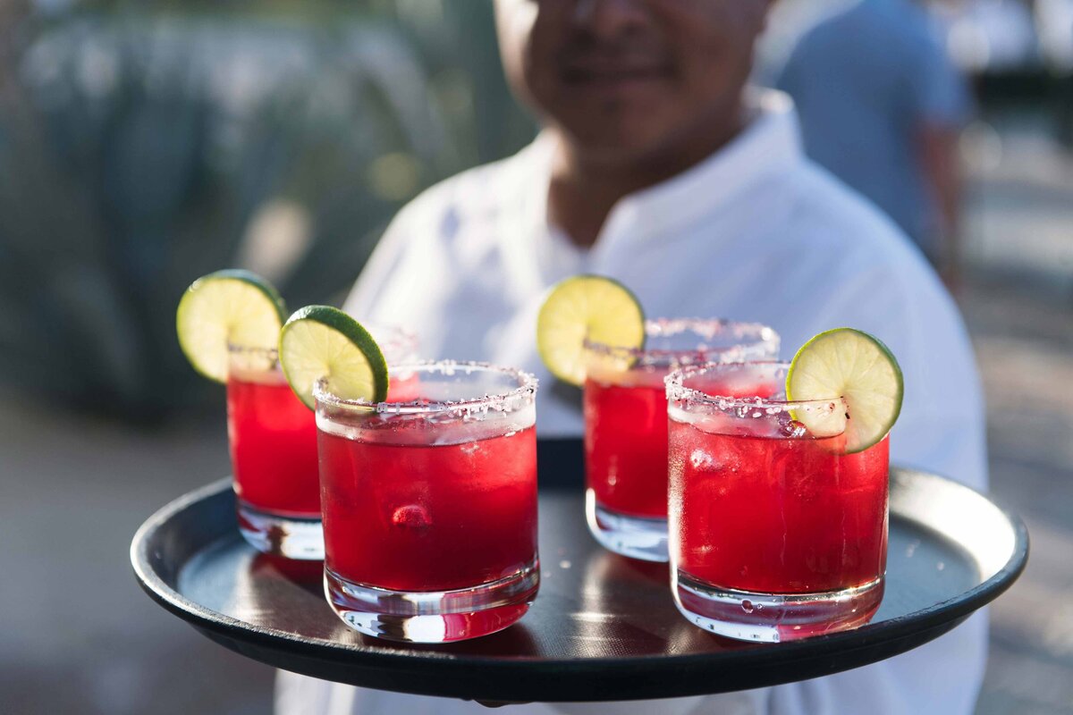 Cocktails being served by a waiter with limes on the edge of the glass