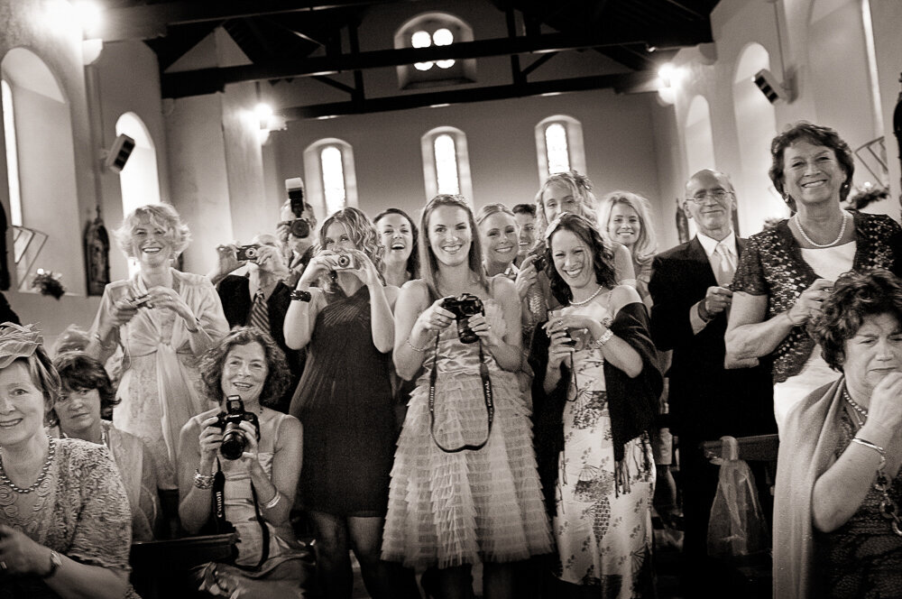 large group of wedding guests taking photographs in Kenmare church