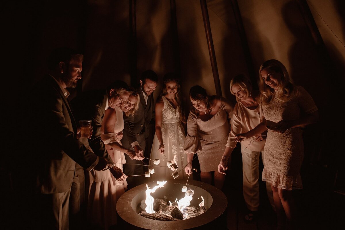 Family gathers around campfire during intimate wedding celebration