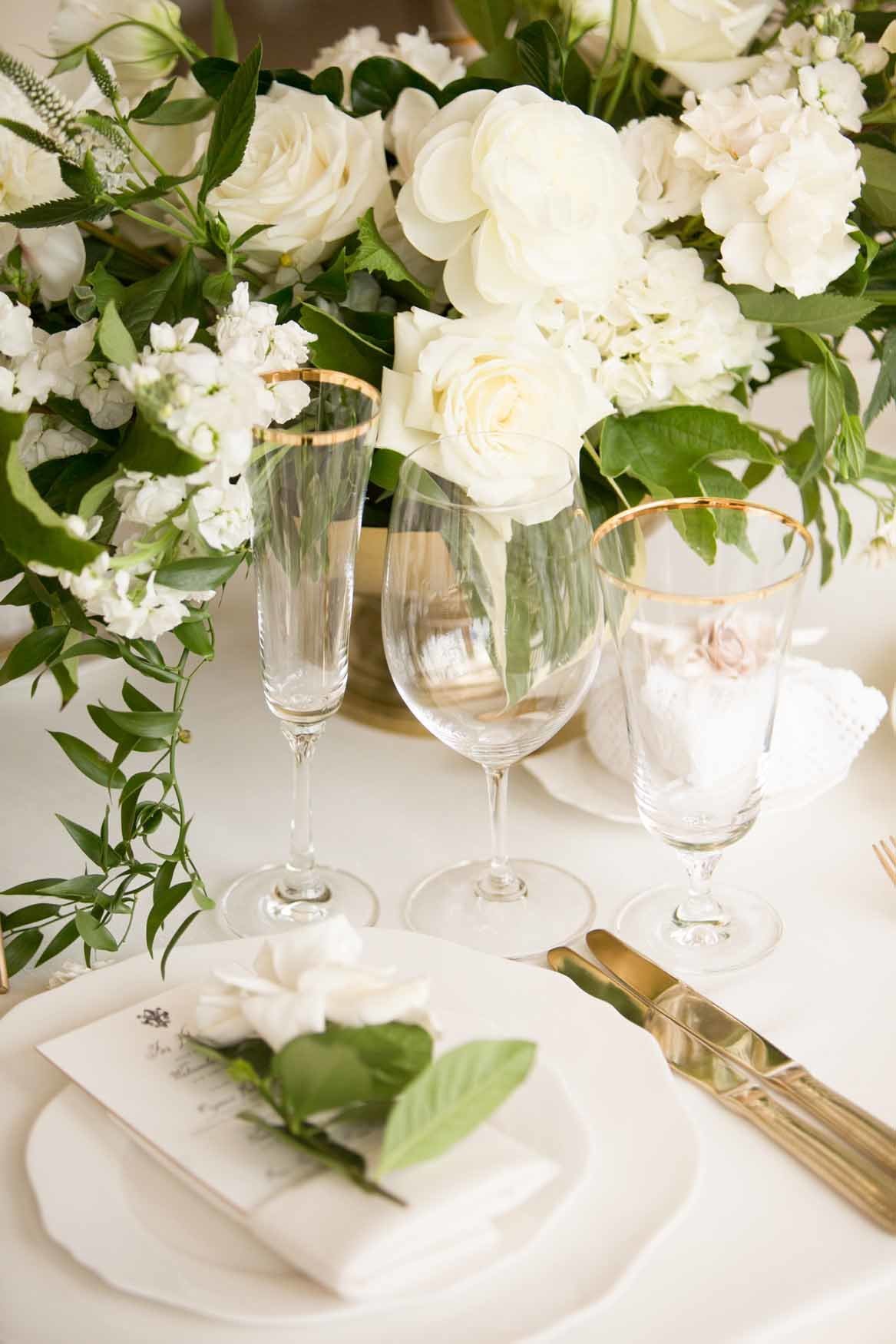 Luxurious white and gold table setting with gardenia napkin flower