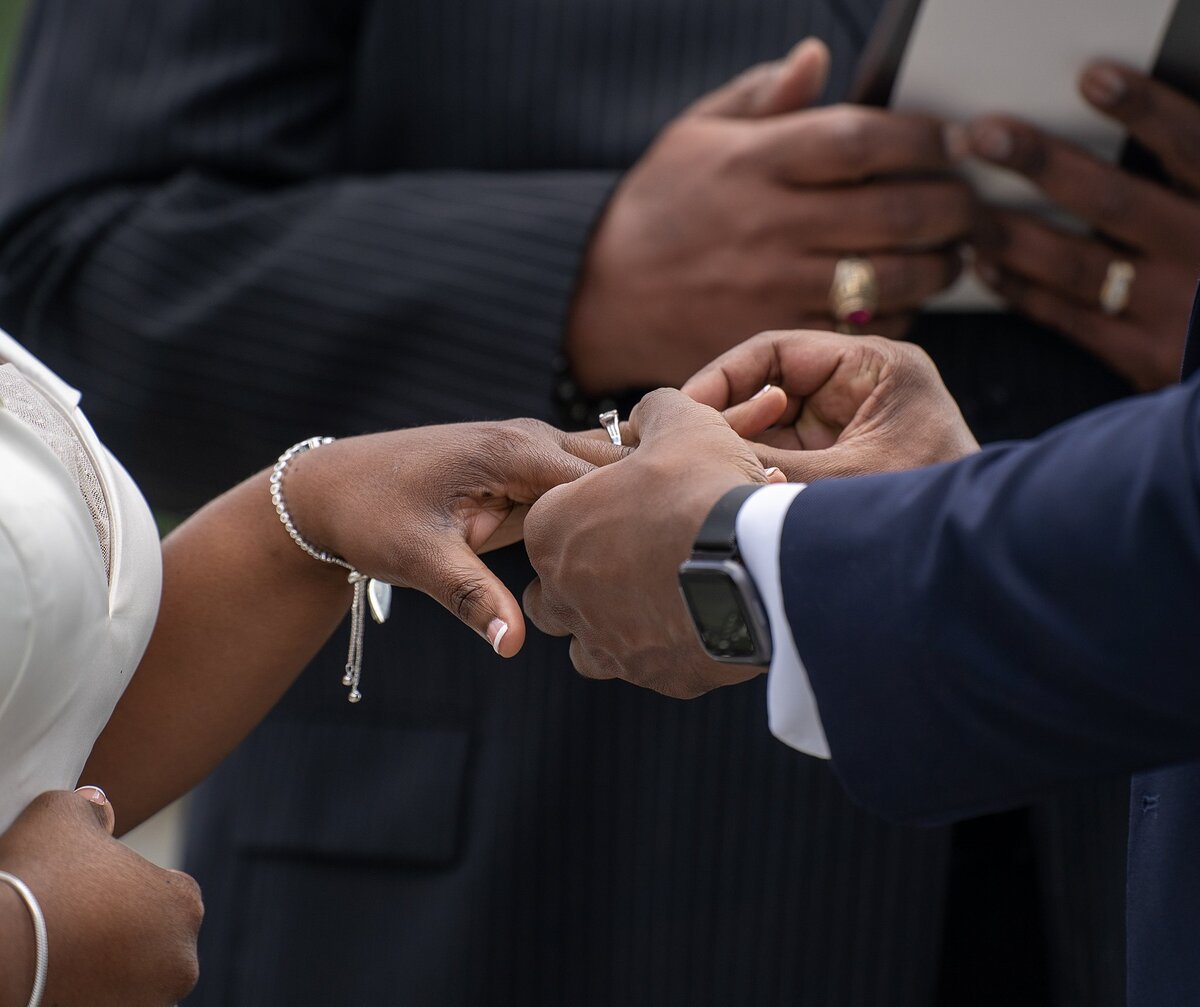Groom places ring on bride's finger during ceremony at the Fawn Lake Country Club