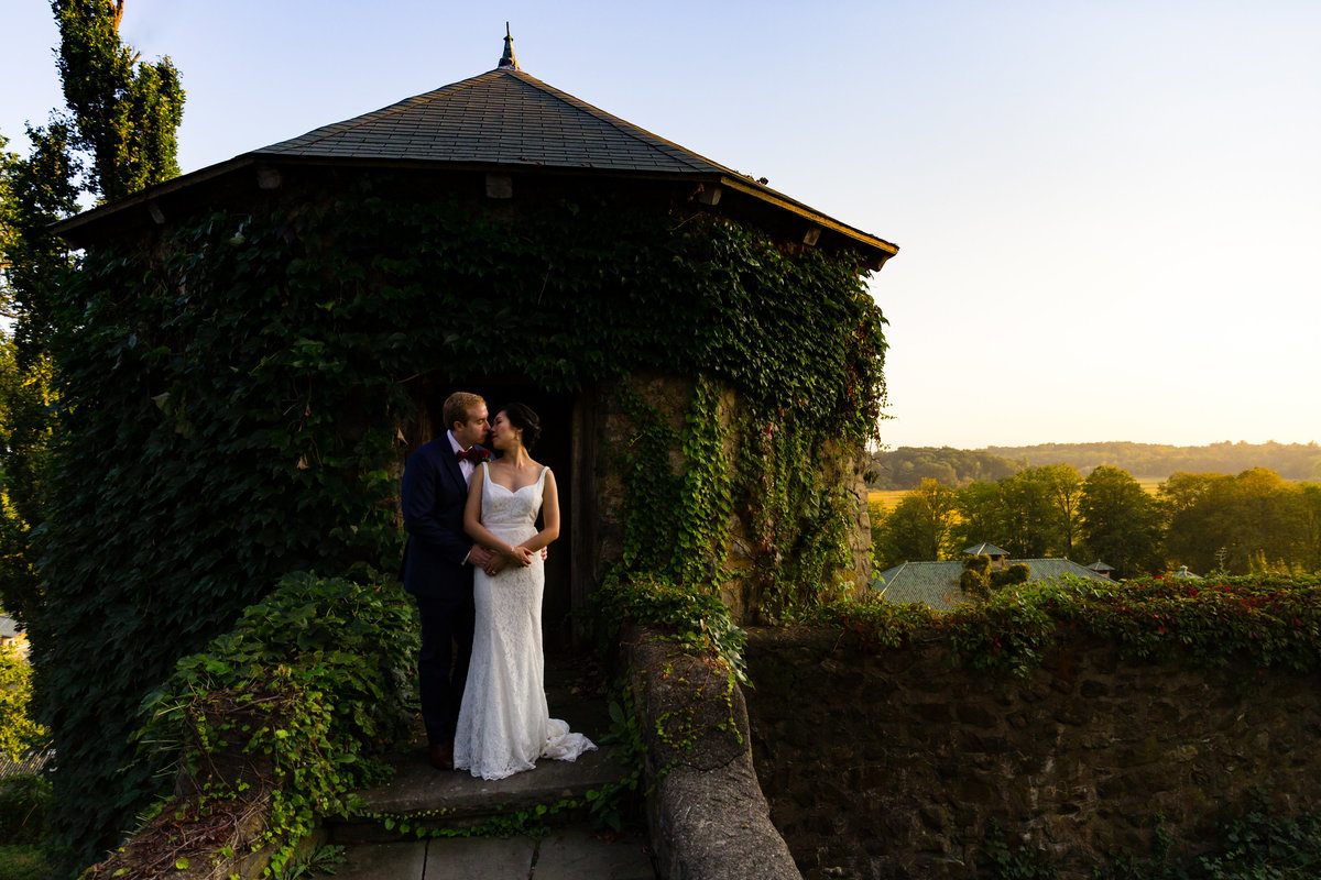 The Barn at Crane Estate wedding venue serves as a gorgeous backdrop for this kissing couple at sunset