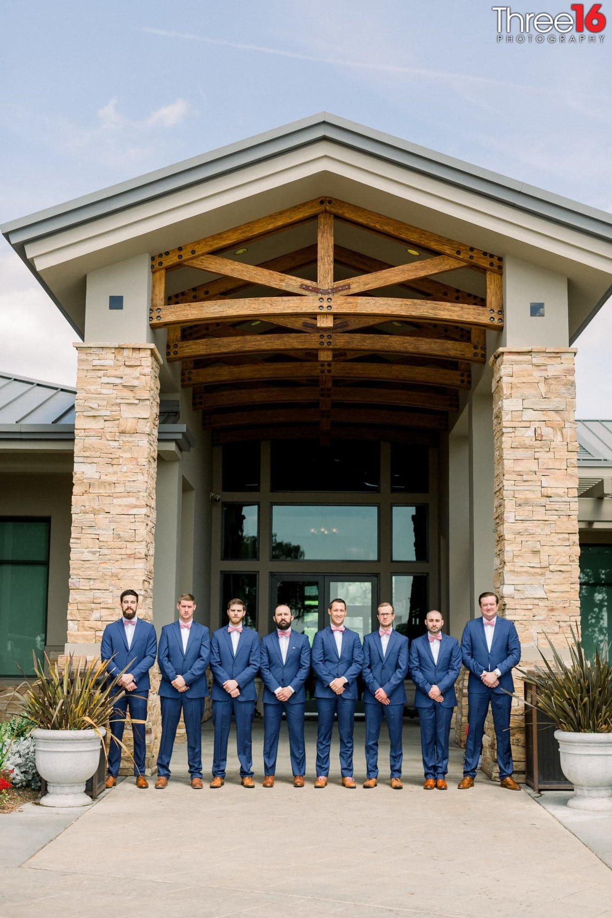 Groomsmen line up in their blue suits in front of the Black Gold Golf Course entrance