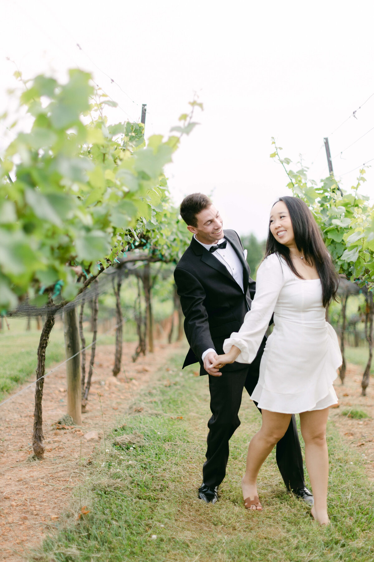 A bride and groom dance in a vineyard.
