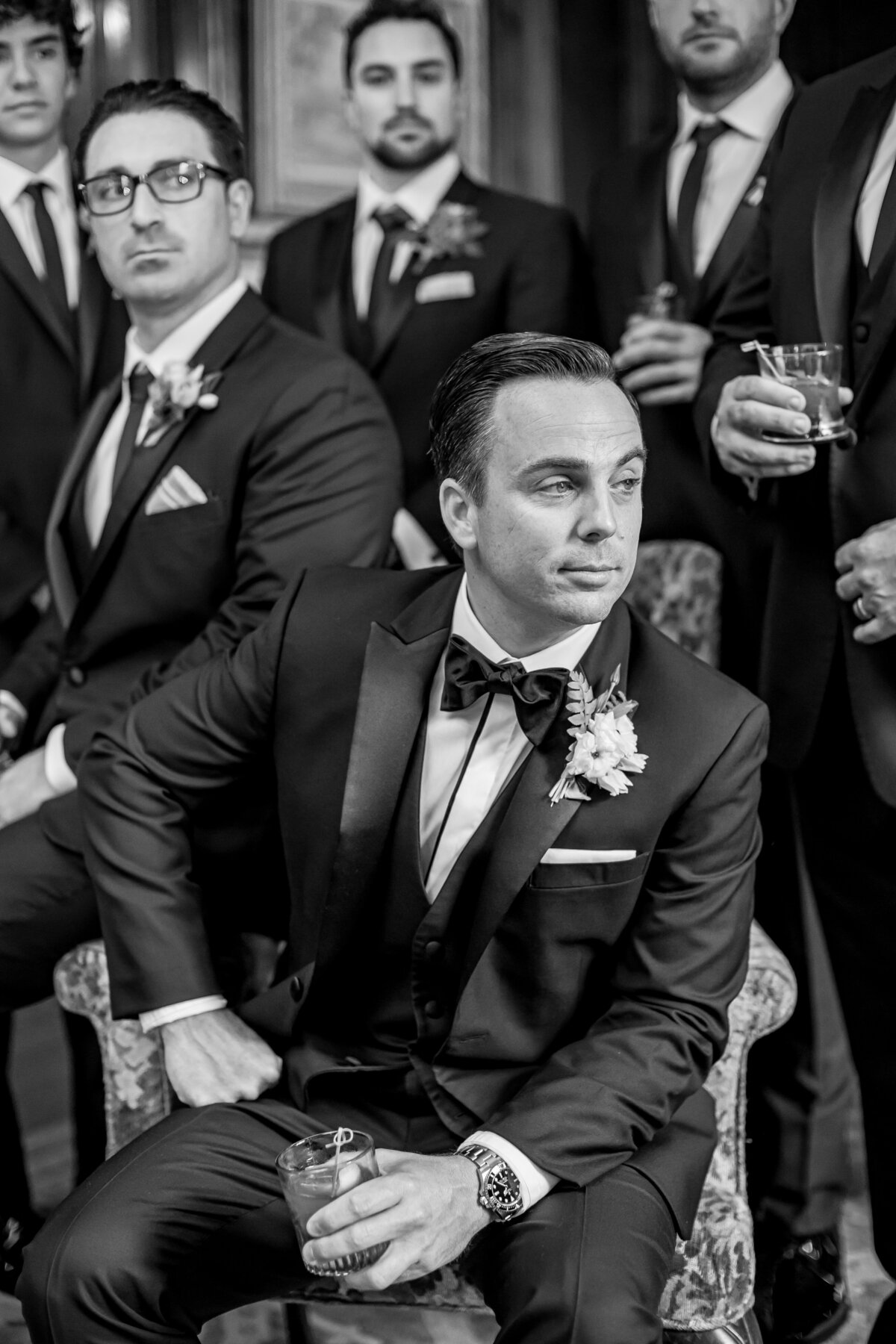 black and white photo of handsome groom with his groomsmen and a beverage