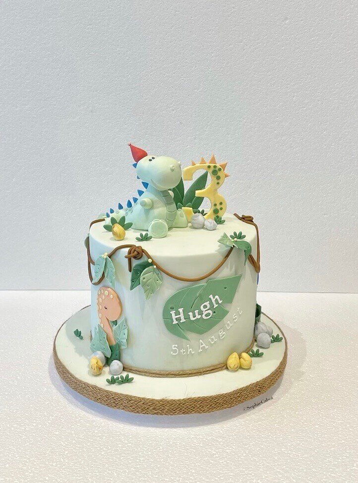 A dinosaur themed birthday cake with a dinosaur model on top