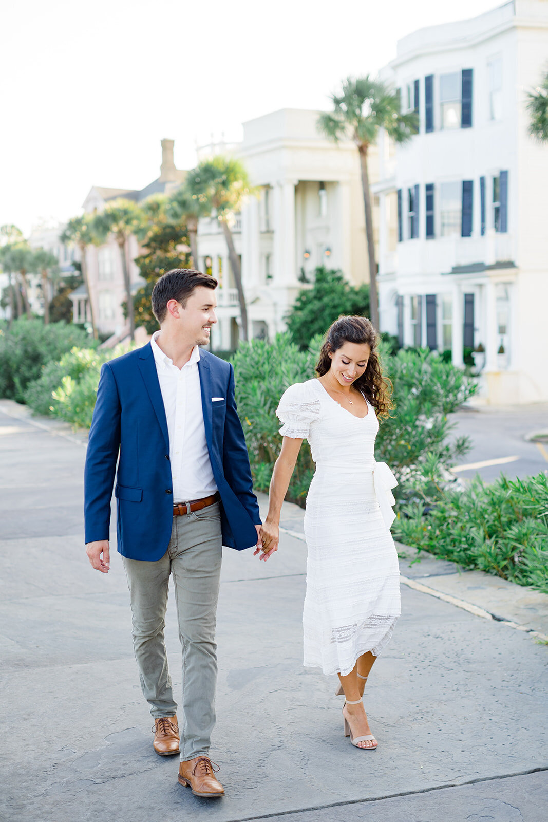 Engagement session with couple walking on the battery in downtown Charleston. Palm trees and historic houses. Sunset engagement photos. Kailee DiMeglio Photography.