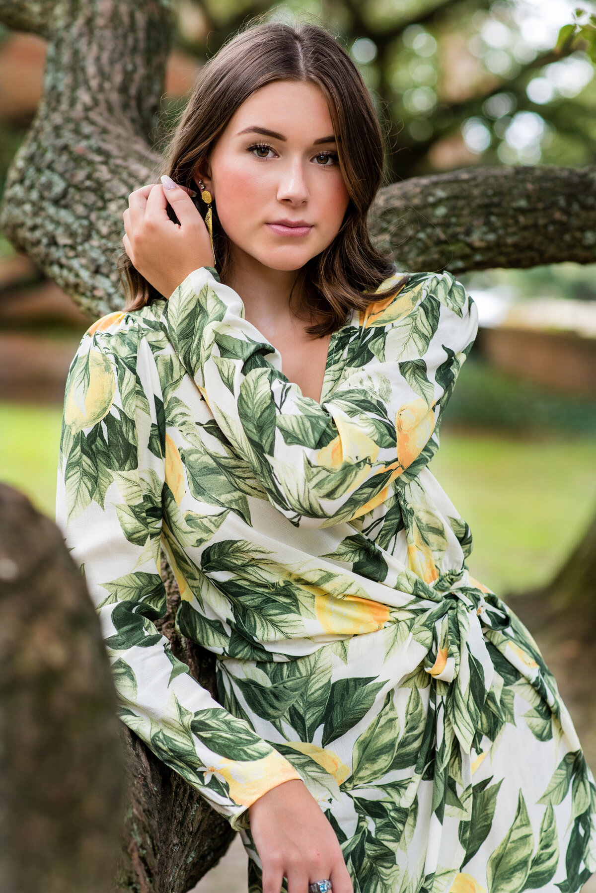Cosby high school girl poses in tree wearing a tropical print jumsuit during her senior portrait session in Williamsburg, VA.