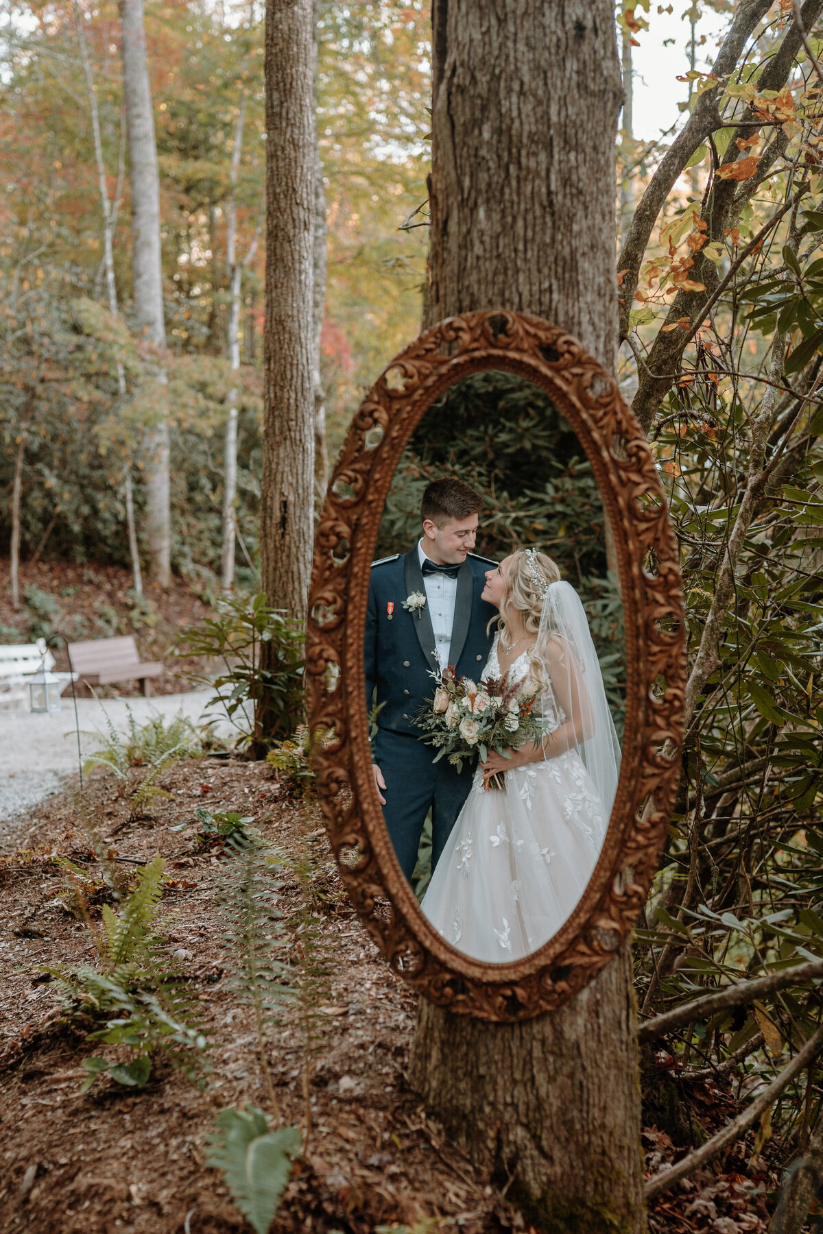 reflection in a mirror of groom in uniform smiling at bride