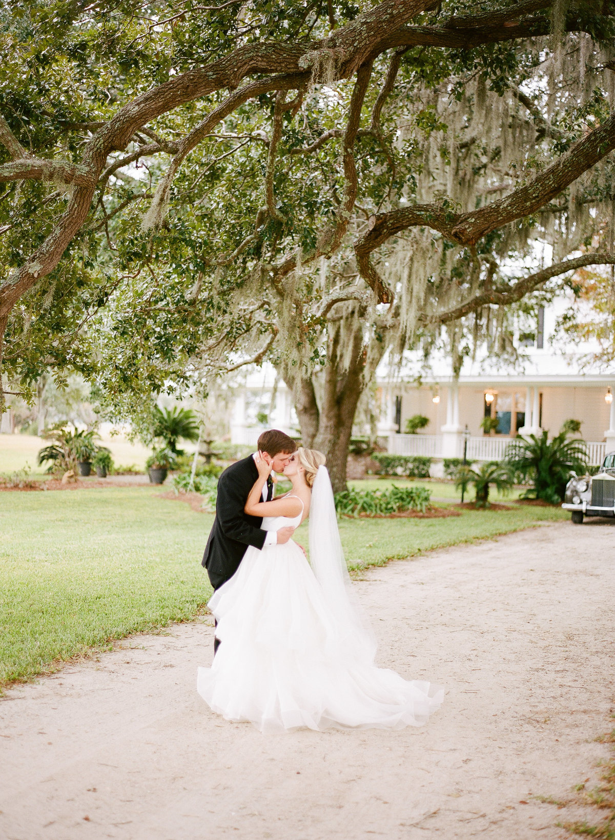 Bride and Groom Newlywed Kiss Charleston Wedding Couple Portraits Underneath Spanish Moss Oak Trees