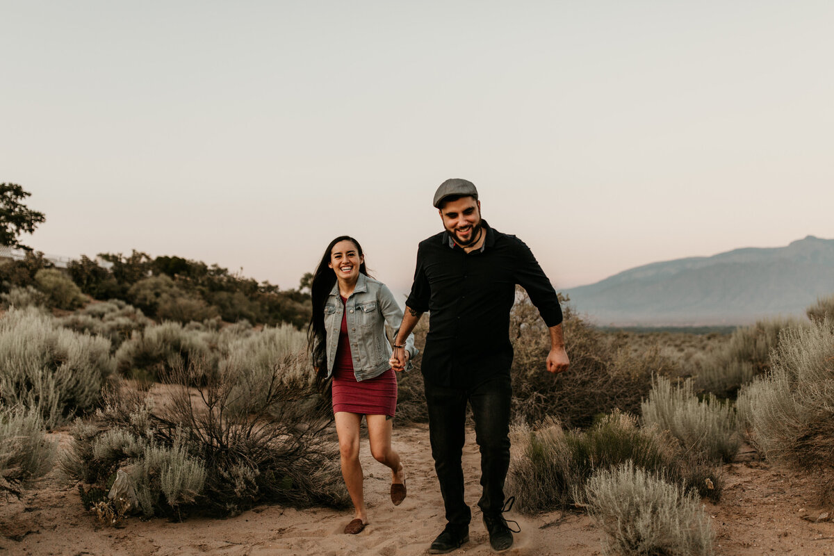 engaged couple running in the desert