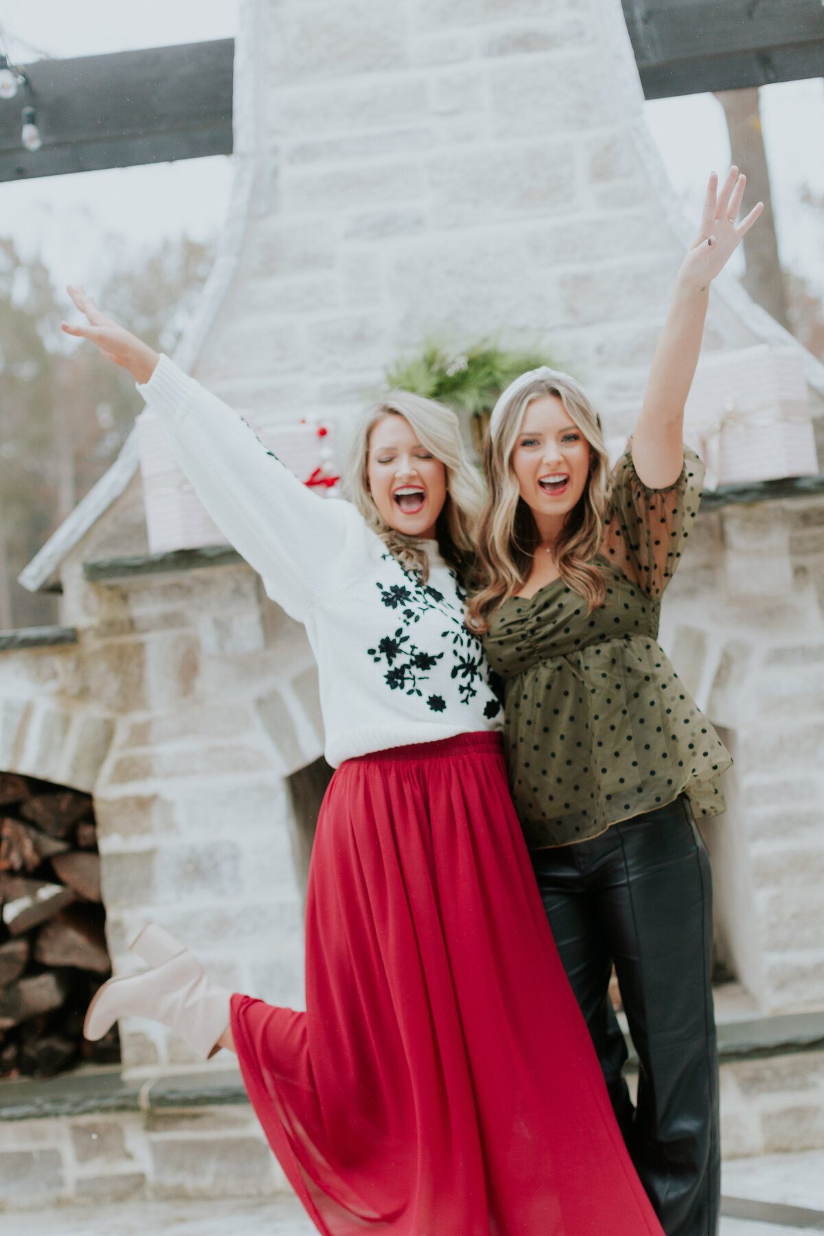 Holiday celebration brand photo of Emily Odom & Brook Issac of Enhanced by EB laughing with hands in the air outside in South Charlotte