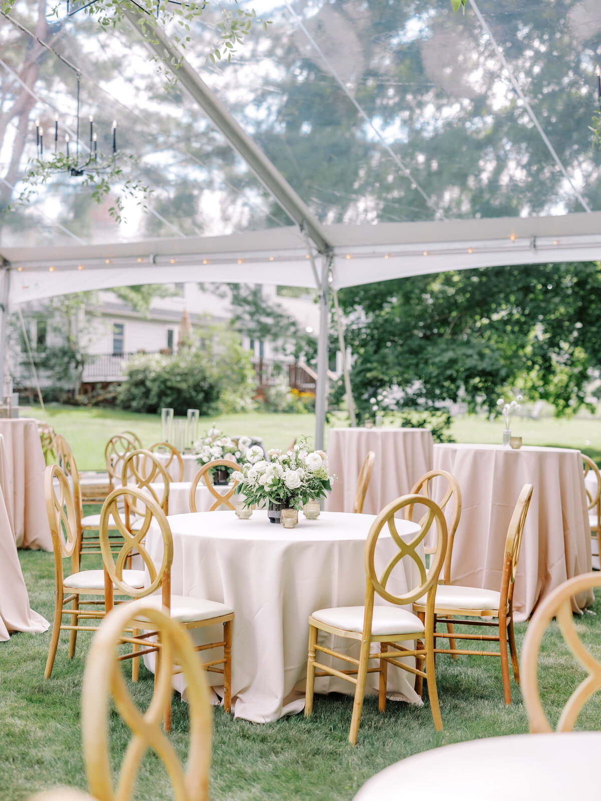 Wedding reception tables and chairs with floral centerpieces under a clear tent