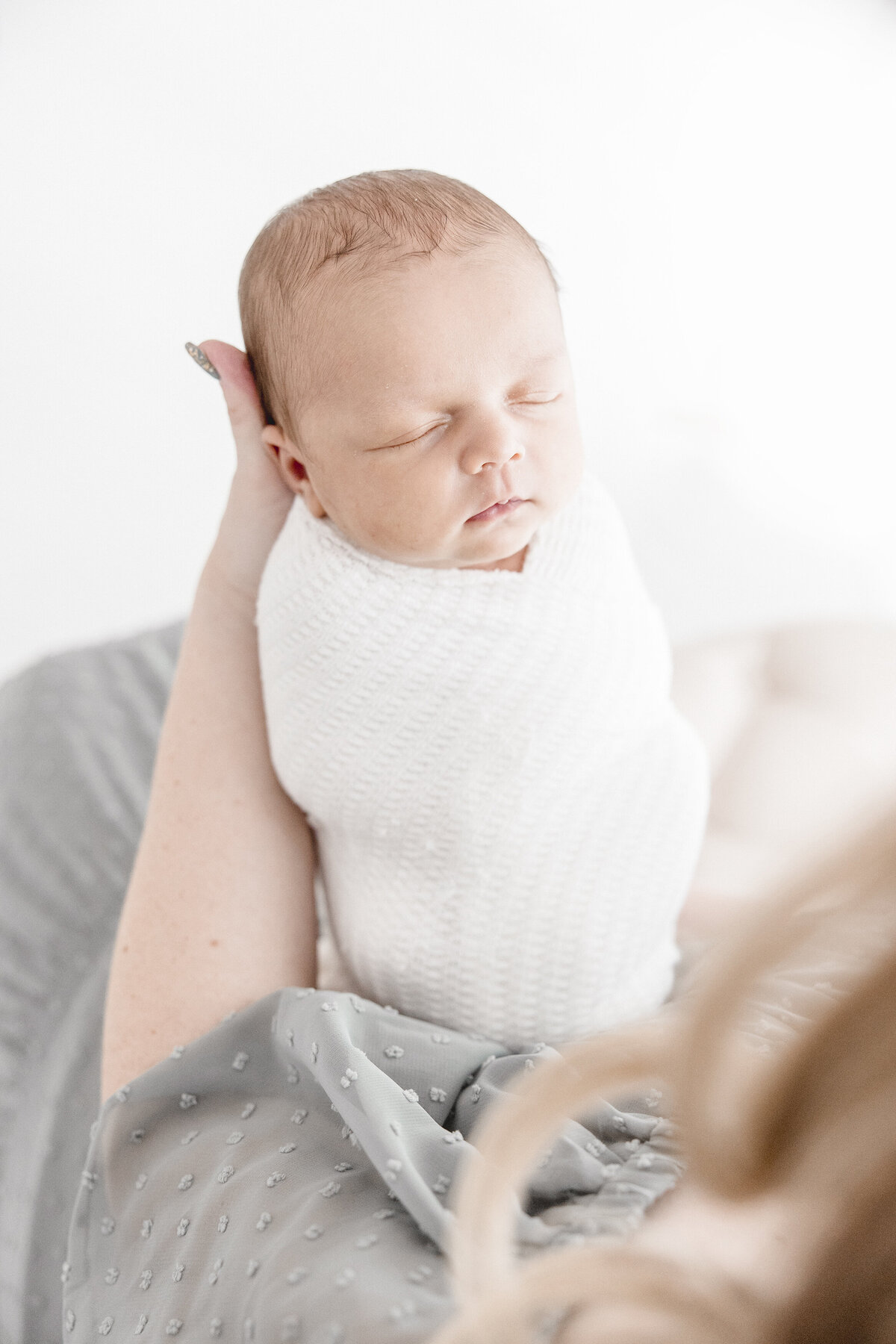 Baby sleeping white wrap being held by mother