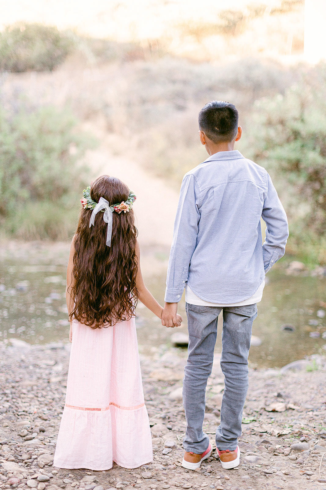 siblings holding hands looking at river