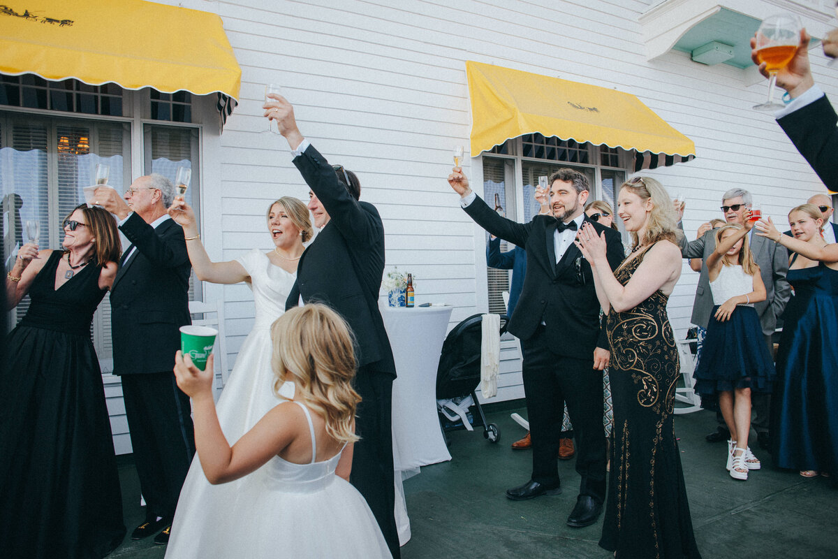 a wedding couple cheers as a flower girl mimicks them and holds up her water as well