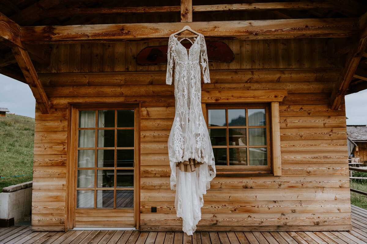 Bride's elopement dress against cozy cabin in the Italian Dolomites