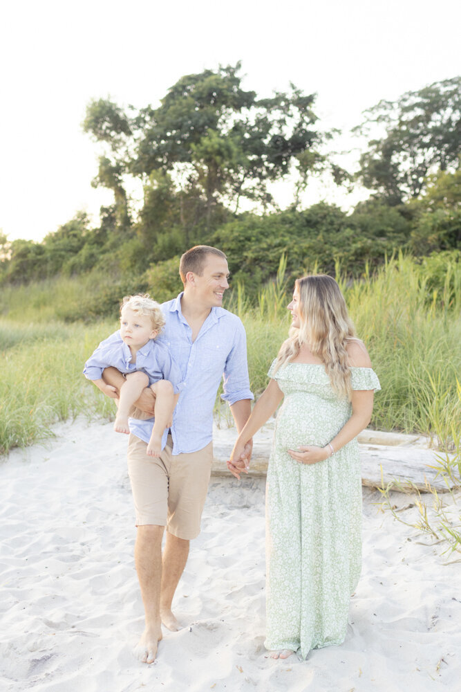 young family walking on the beach during maternity photos