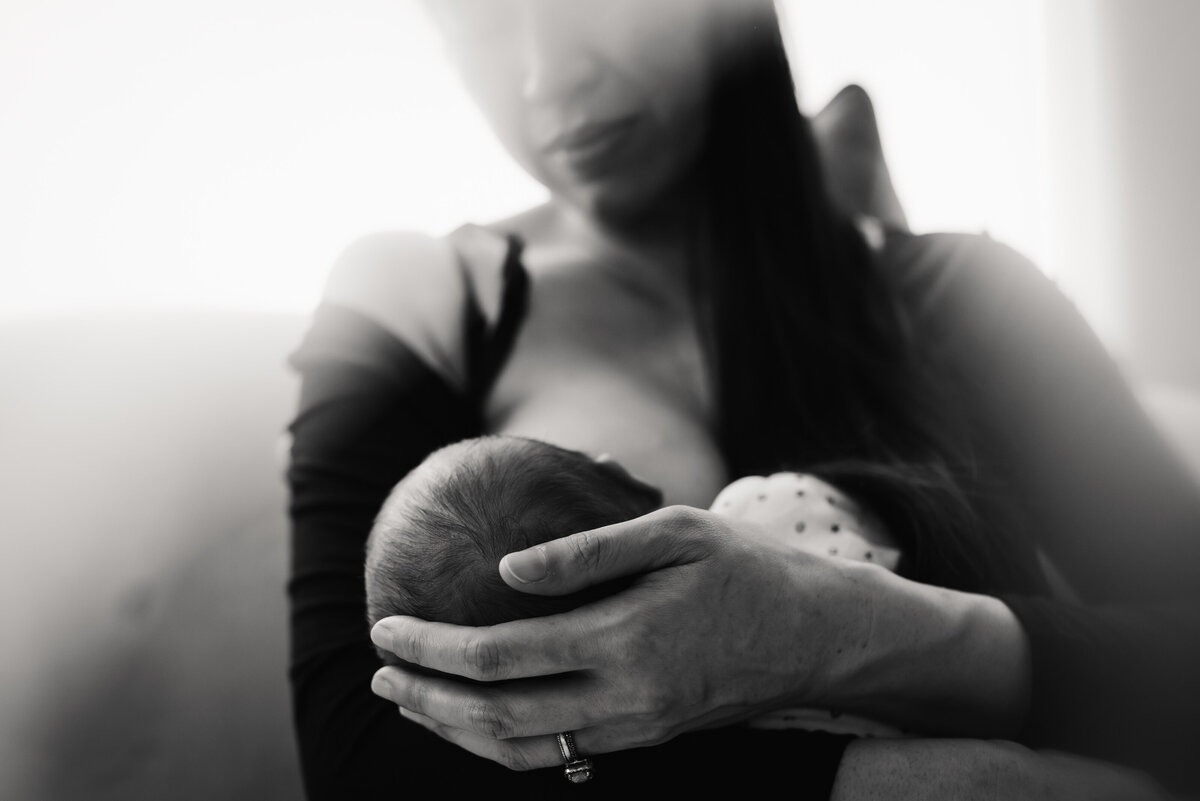 Mother breastfeeding newborn baby in black and white