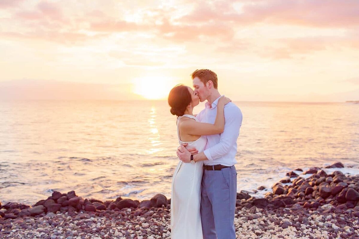 Honeymooning couple on Maui photographed by Love + Water kiss just before sunset in Wailea