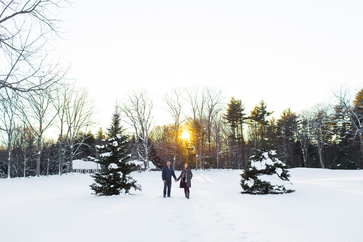 Couple stands in the deep snow in Newmarket NH as the sun sets behind them