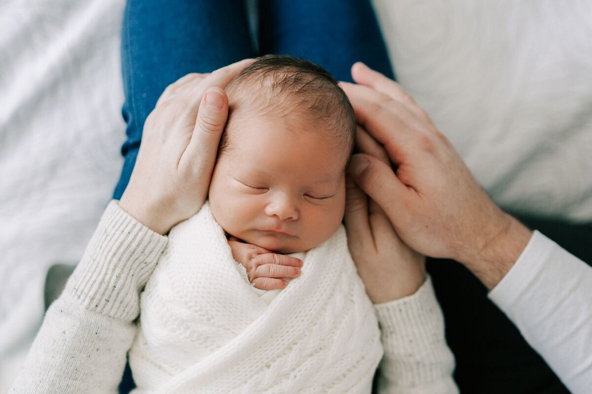 Baby is held on parent's lap during his newborn photography session