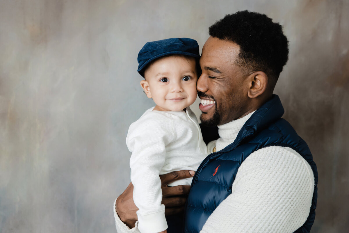 dad holds son in a close hat at studio