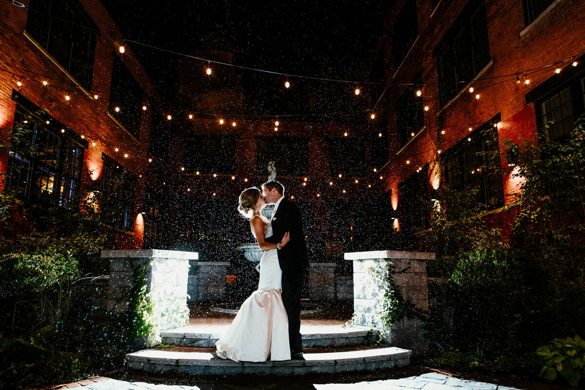 Bride and groom kissing outside in the rain with fairy lights in Buffalo, New York