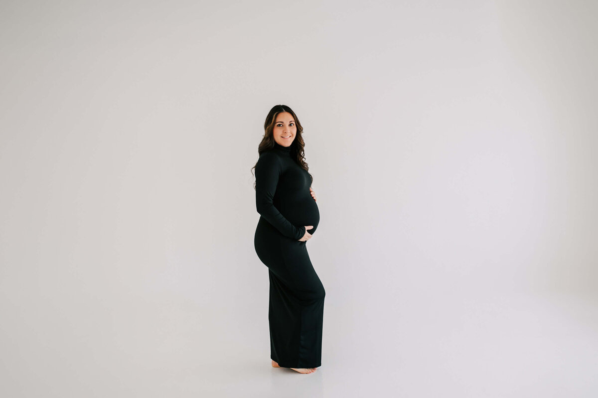 maternity photo in Springfield MO of mom holding baby bump in black dress
