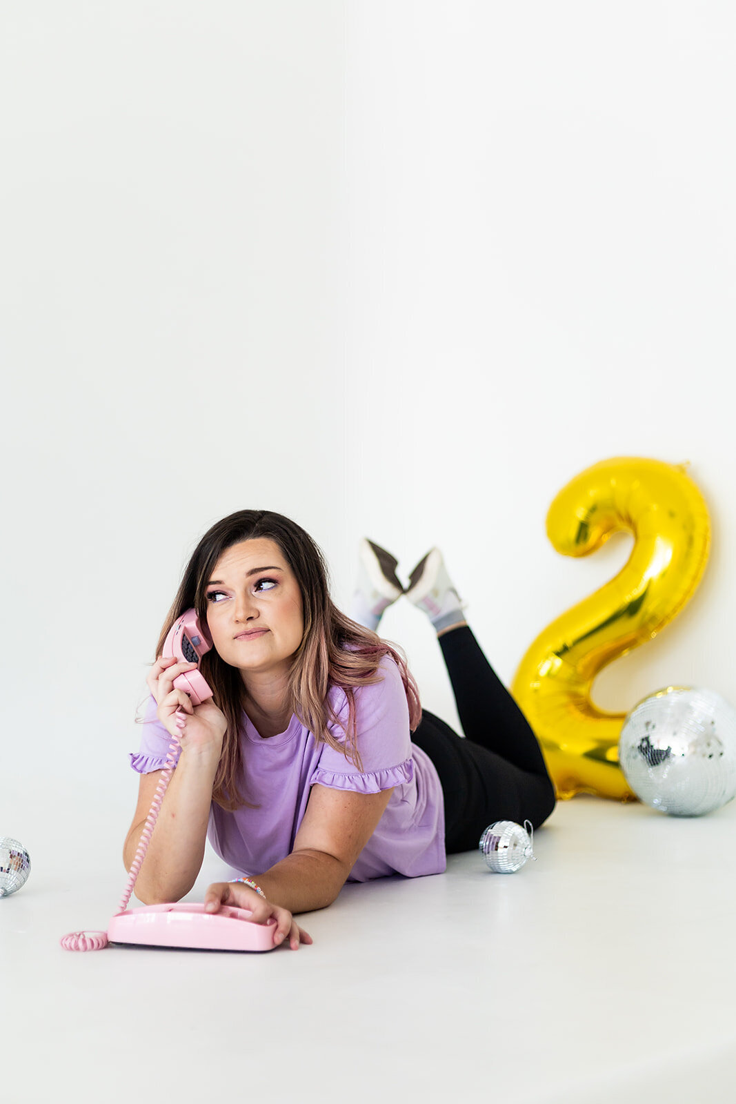 Woman Founder with dark hair in purple shirt of Florida Social Butterfly on a pink phone representing contacting her business